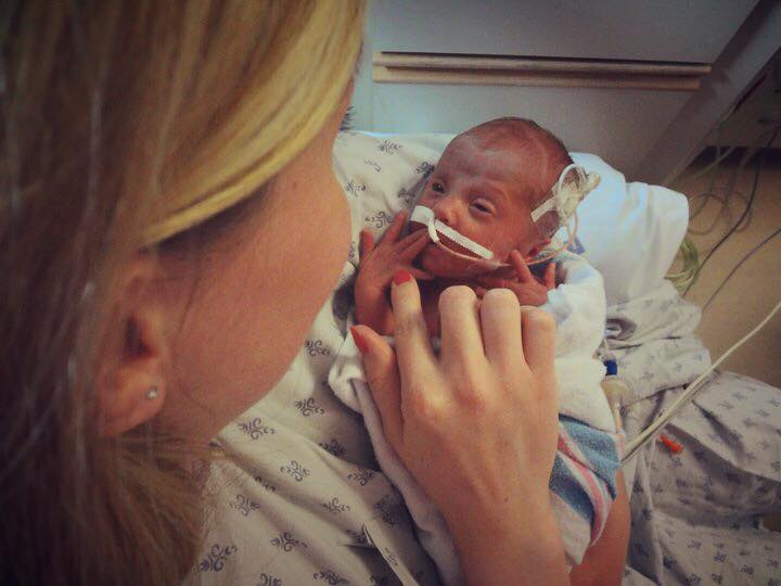 A woman holding her baby in a hospital.