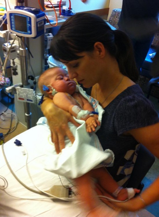 A mother hold her baby, sitting in the hospital. 