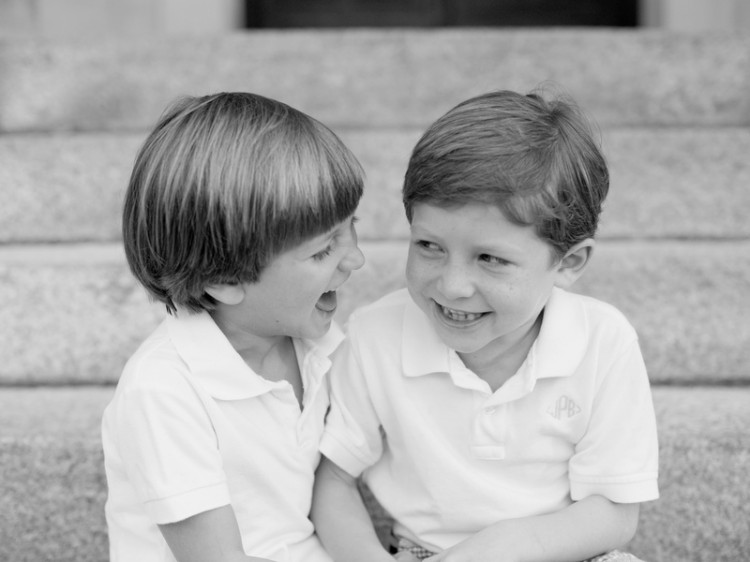Black and white photo of the author's sons wearing white polo shirts, looking at each other and laughing