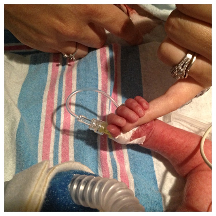 A little newborn baby holds his mom's finger. 