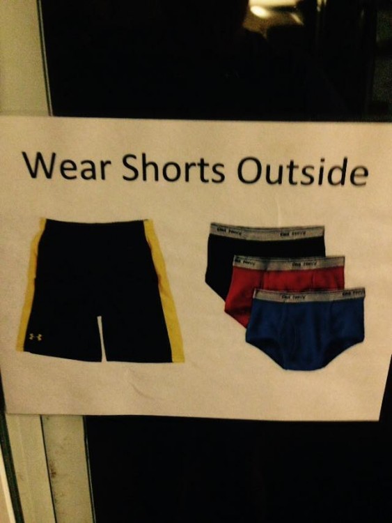 A sign that says "Wear Shorts Outside" and as a picture of a pair of black shorts with a yellow stripe and pairs of black, red and blue underwear