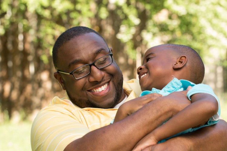 African American father and son hugging and laughing