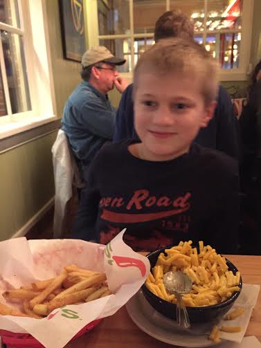 author's son at a restaurant eating fries and macaroni 