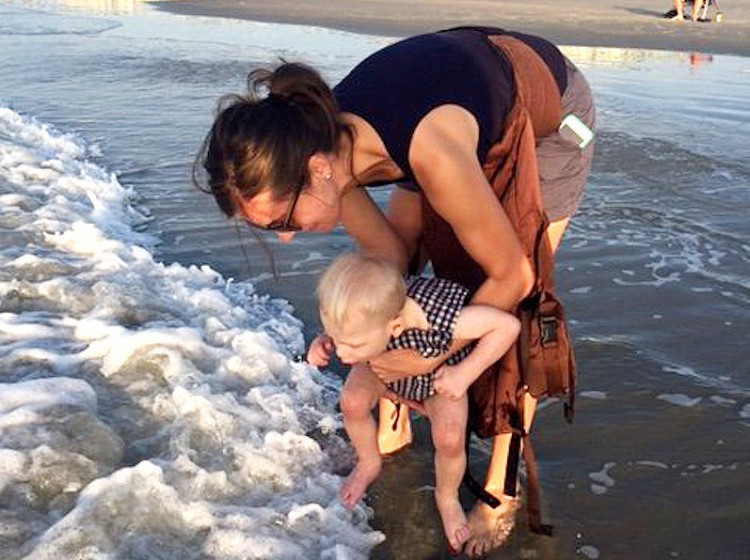 The author with her son at the beach. He's dipping his toes in water while she holds him.