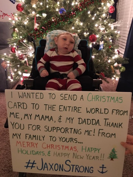 author's son in front of christmas tree with sign that says "I wanted to send a christmas card to the entire world from me, my mama, and dadda. Thank you for supporting me. Happy Holidays and Happy New Year. #JaxonStrong."