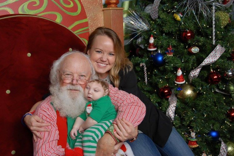 Mother, son, and Santa on chair with christmas tree