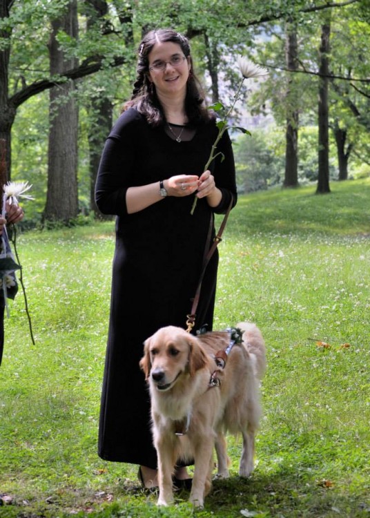 woman standing on grass next to dog