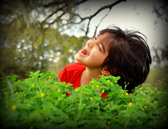 Girl smiling outdoors in front of a plant