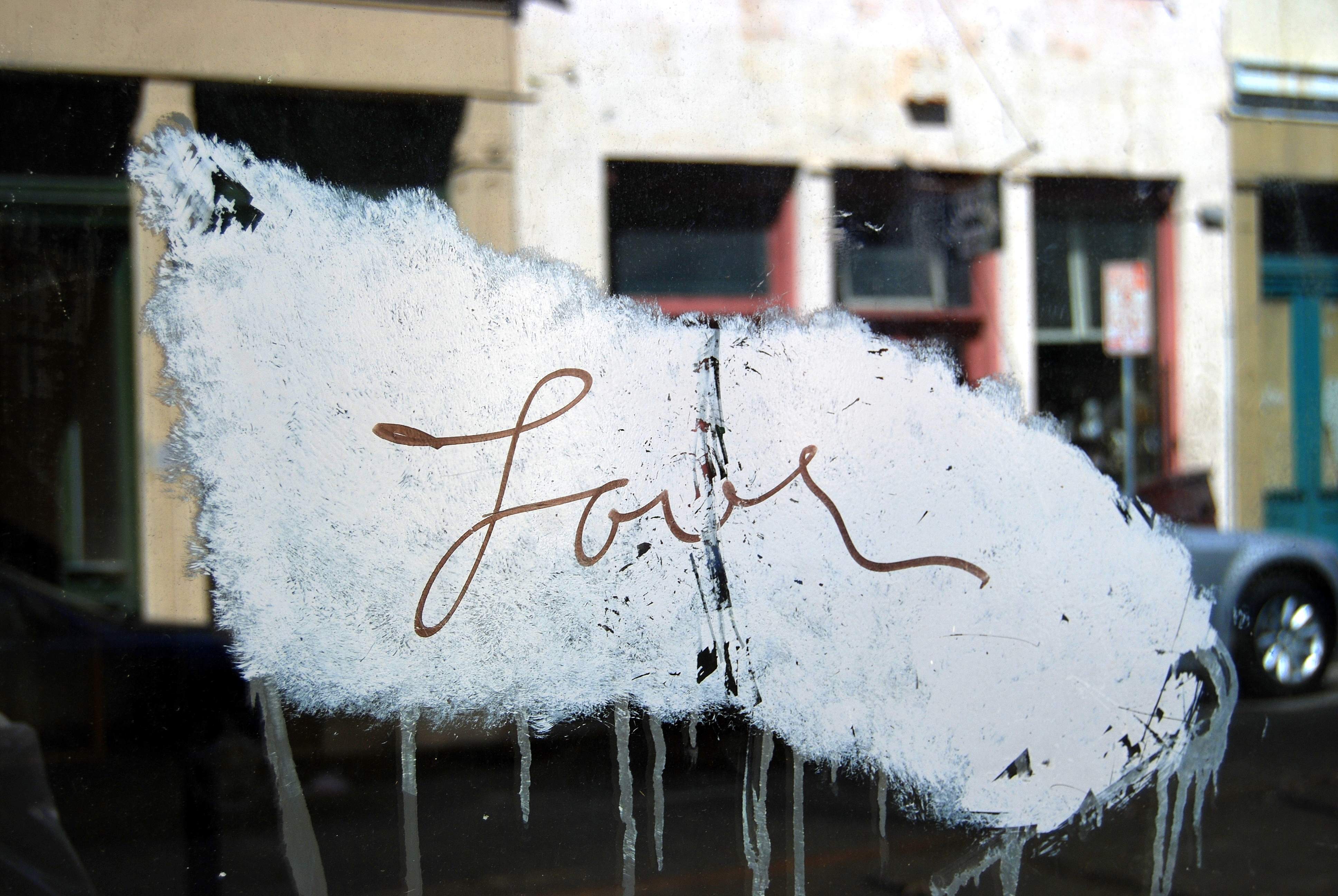 The word "love" written in cursive across a photo of a street