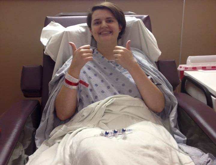 Woman giving thumbs-up sign in hospital bed