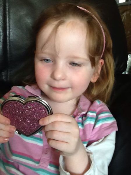Little girl holding heart-shaped pink mirror