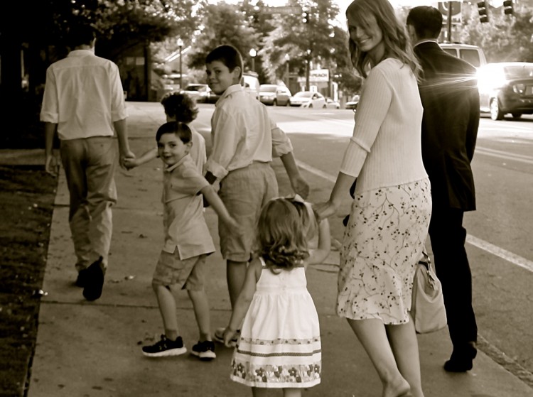 black and white photo of parents walking with kids holding hands