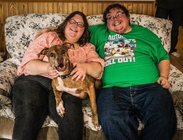 woman and man sitting on couch with dog