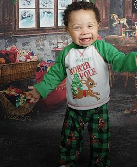 Jadon wearing a long-sleeved green, red and white shirt that says "Next Stop North Pole"