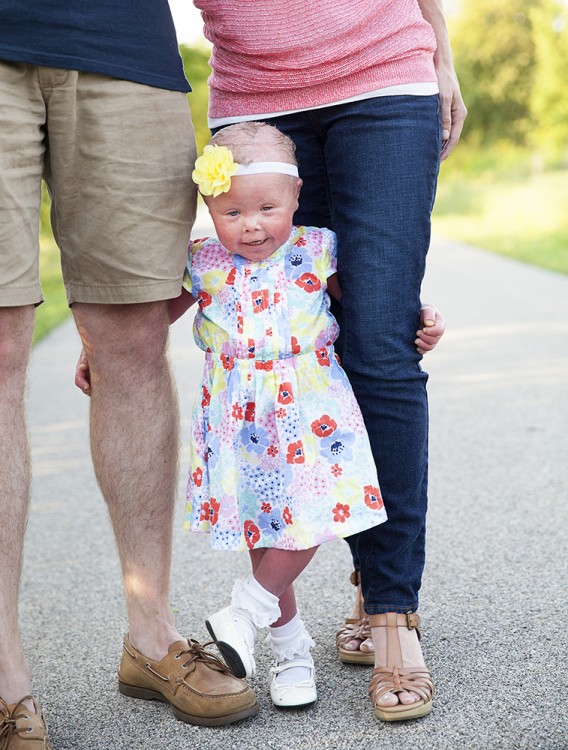 baby standing between parents legs