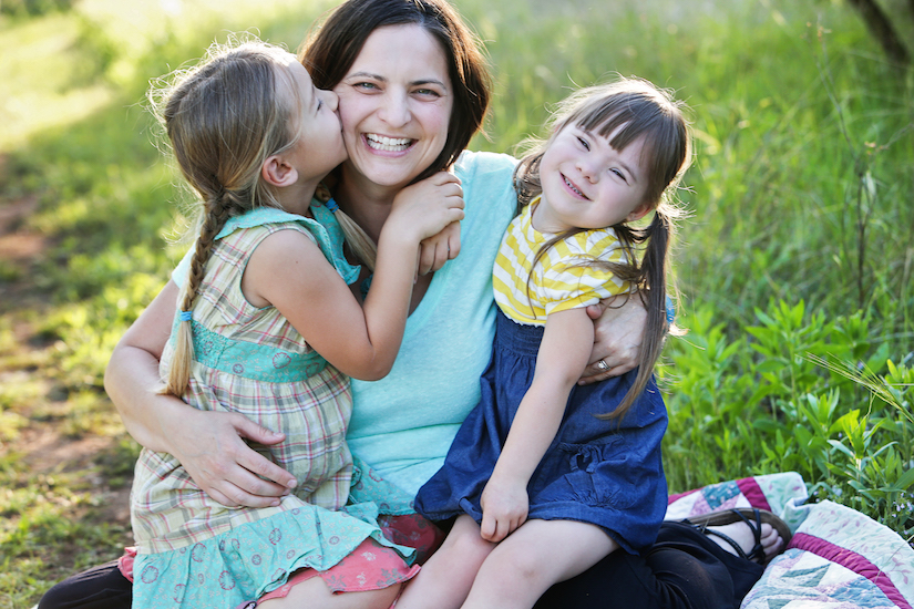 Mom with two daughters sitting outside on the grass