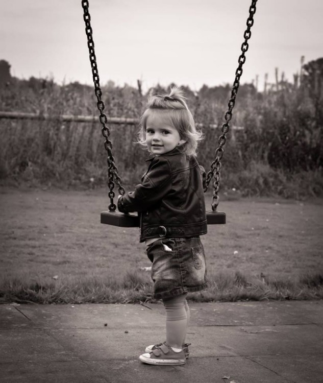 A young girl smiling on a swing. 