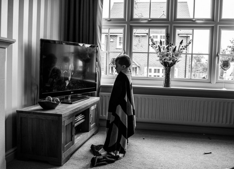 A young boy standing very close to a TV. 