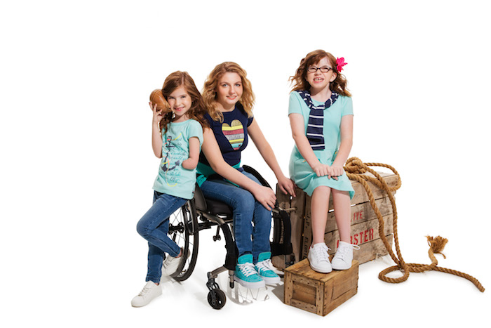 Three children, one in a wheelchair, wearing adaptable clothing. 