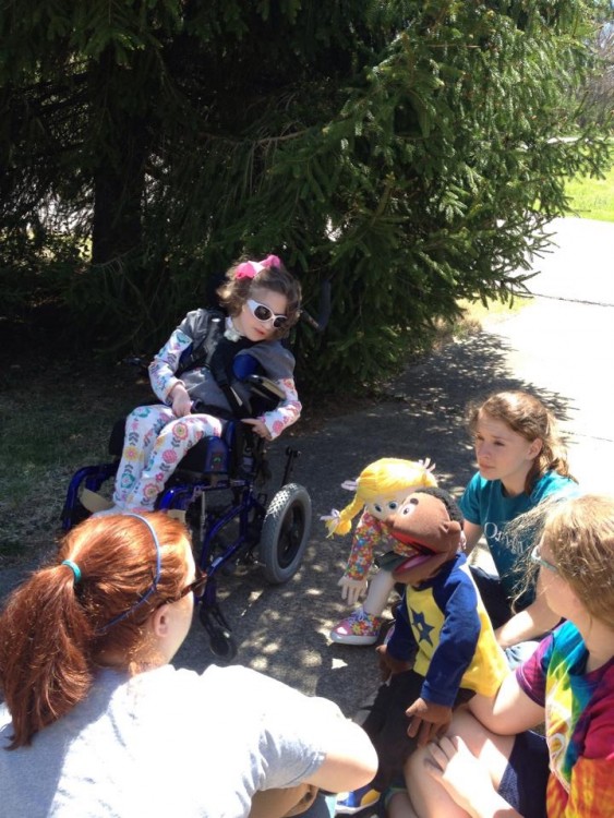 women performing puppet show for girl in wheelchair