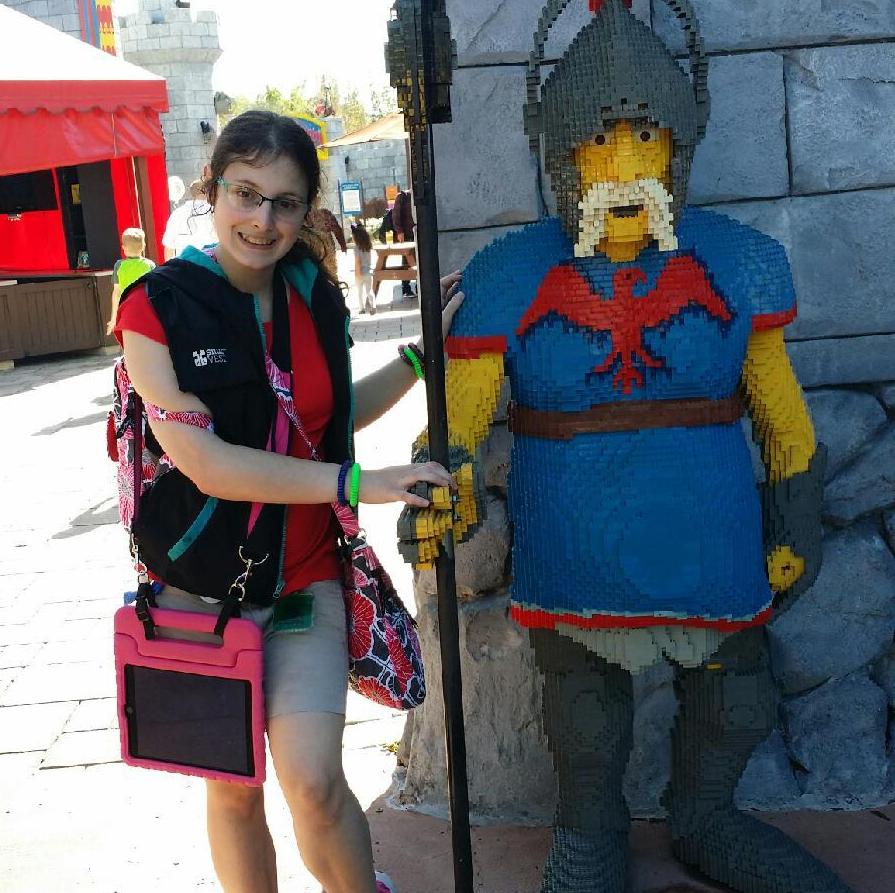 Woman standing next to a statue of a guard made of Legos