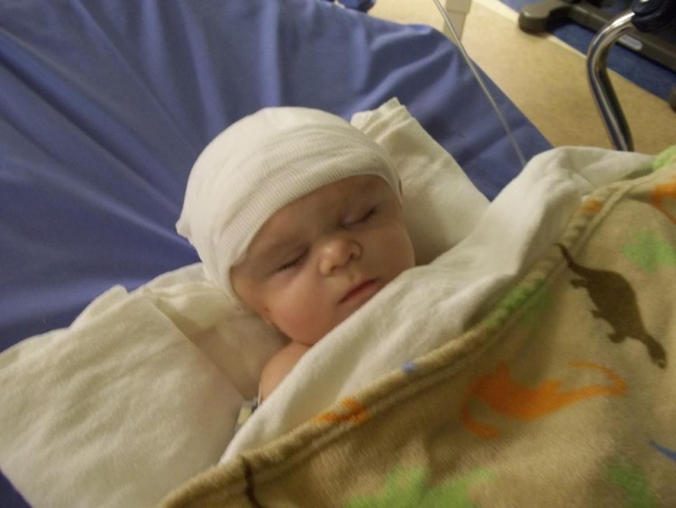 baby with bandage on head in hospital