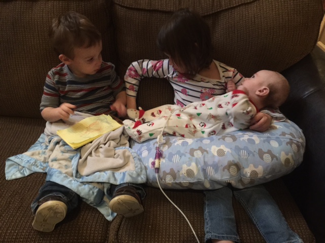 kids feeding baby lying on pillow