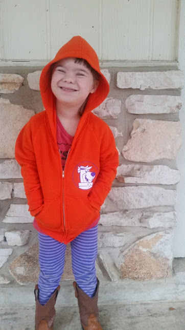 Girl wearing red hoodie and posing in front of a wall