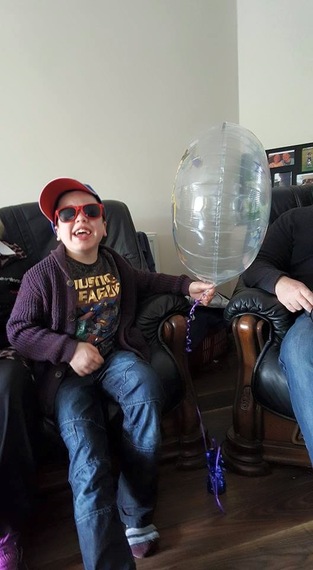 boy on couch holding balloon