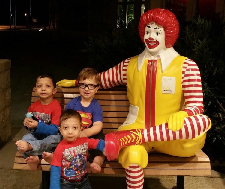three young boys on bench next to ronald mcdonald