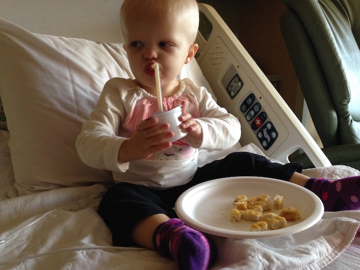 Little girl in hospital bed drinking a beverage