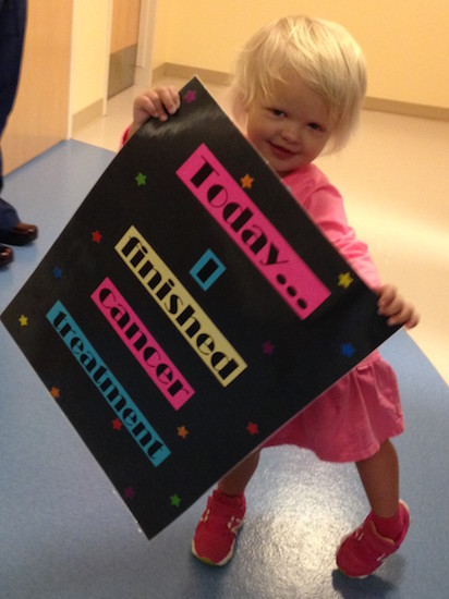 Little girl holding sign that says "Today... I finished cancer treatment"