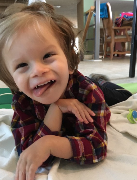 boy lying on stomach wearing plaid shirt