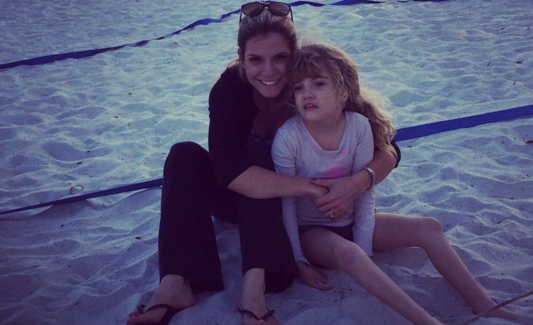 mom and daughter sitting on sand