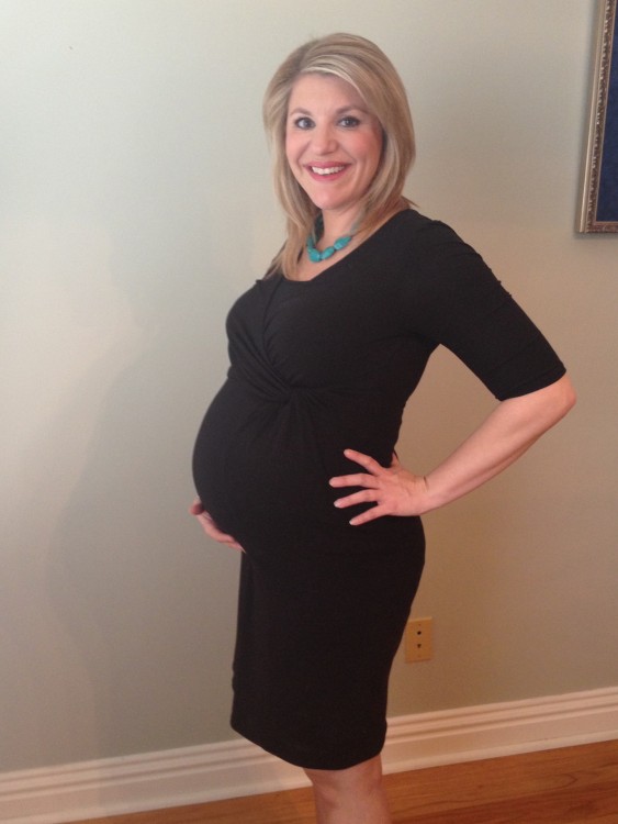 woman in black dress showing off pregnant belly