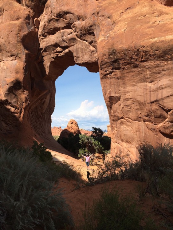 Author standing in front of the arch of a canyon on a hike