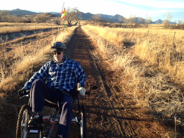Gary riding his trike on a trail through the prairie.