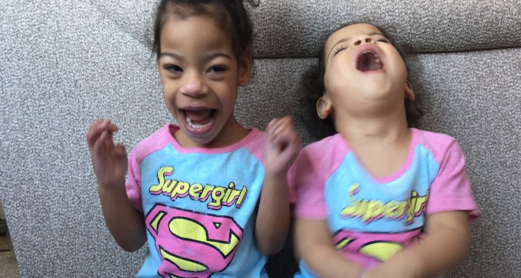 Two young girls laughing wearing matching super girl t-shirts