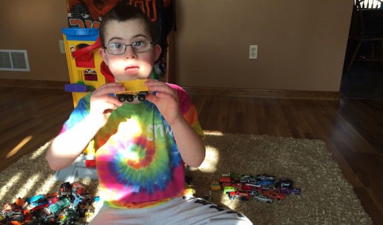 boy in tie-dye shirt playing with toy cars
