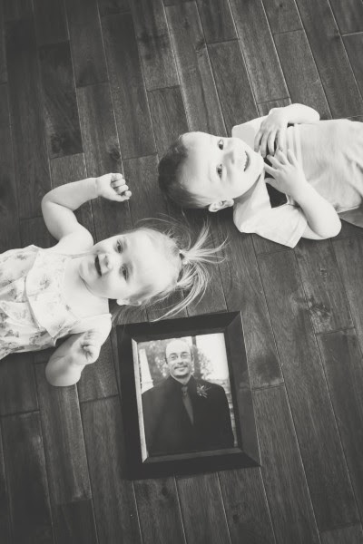 A little boy and girl lay on the floor with a framed picture of a man.