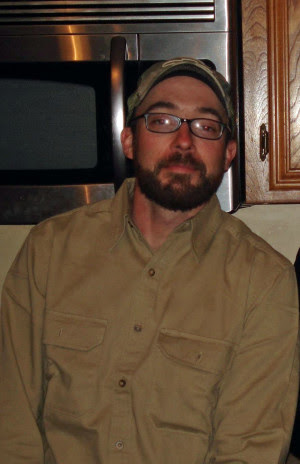 Man wearing a green hat and a green button up shirt. 