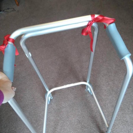 anne's zimmer frame used for walking and balance. two red bows are tied to it.