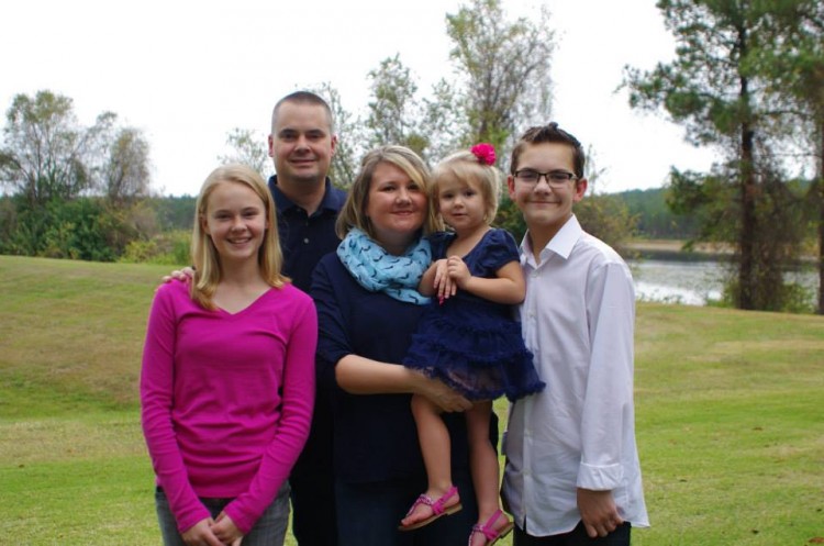 Parents with children smiling on green lawn with lake in background