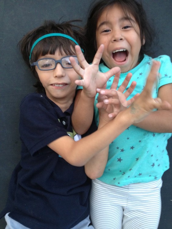 Joel and his sister smiling and reaching their hands out.