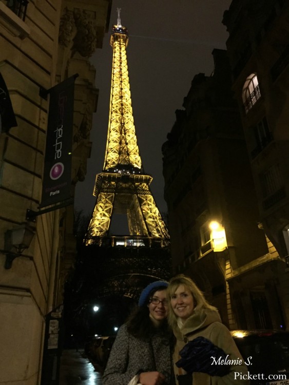 two women in front of eiffel tower at night