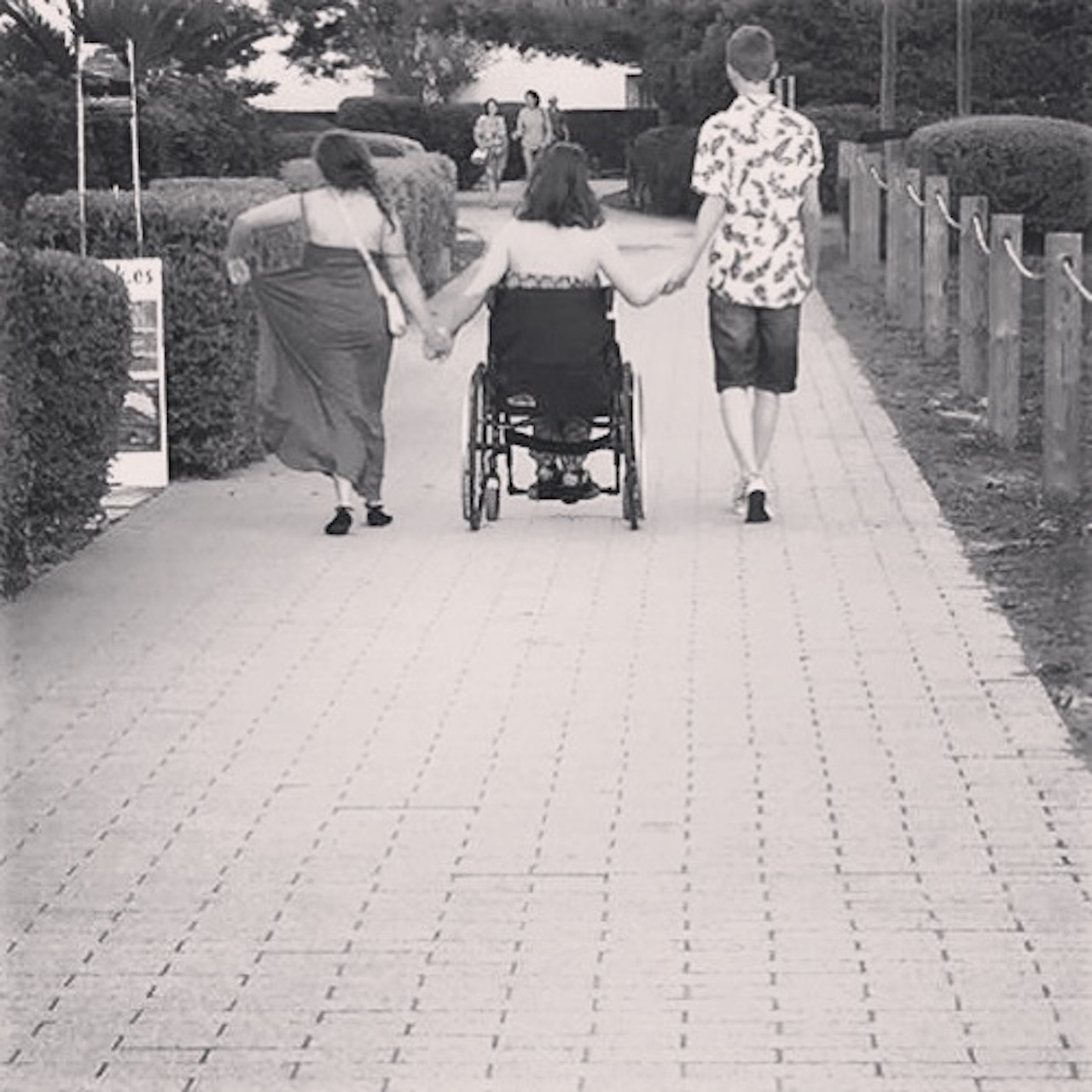 woman in wheelchair holding two friends' hands