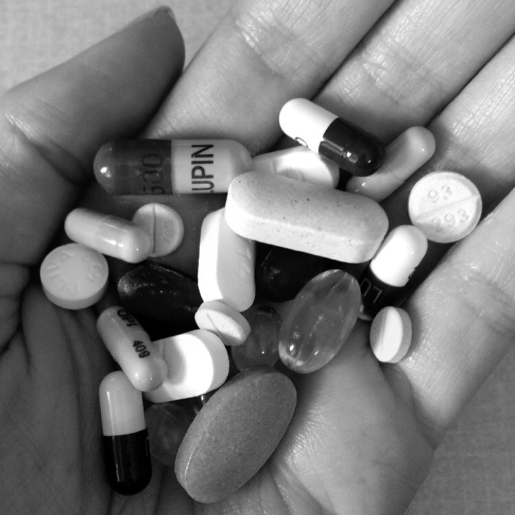 Black and white photo of a hand holding pills