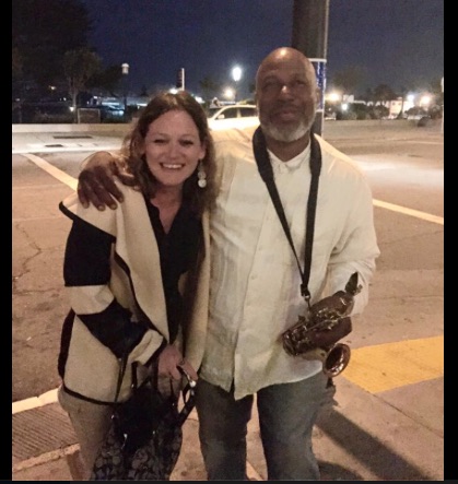 woman standing with saxophone player on the street