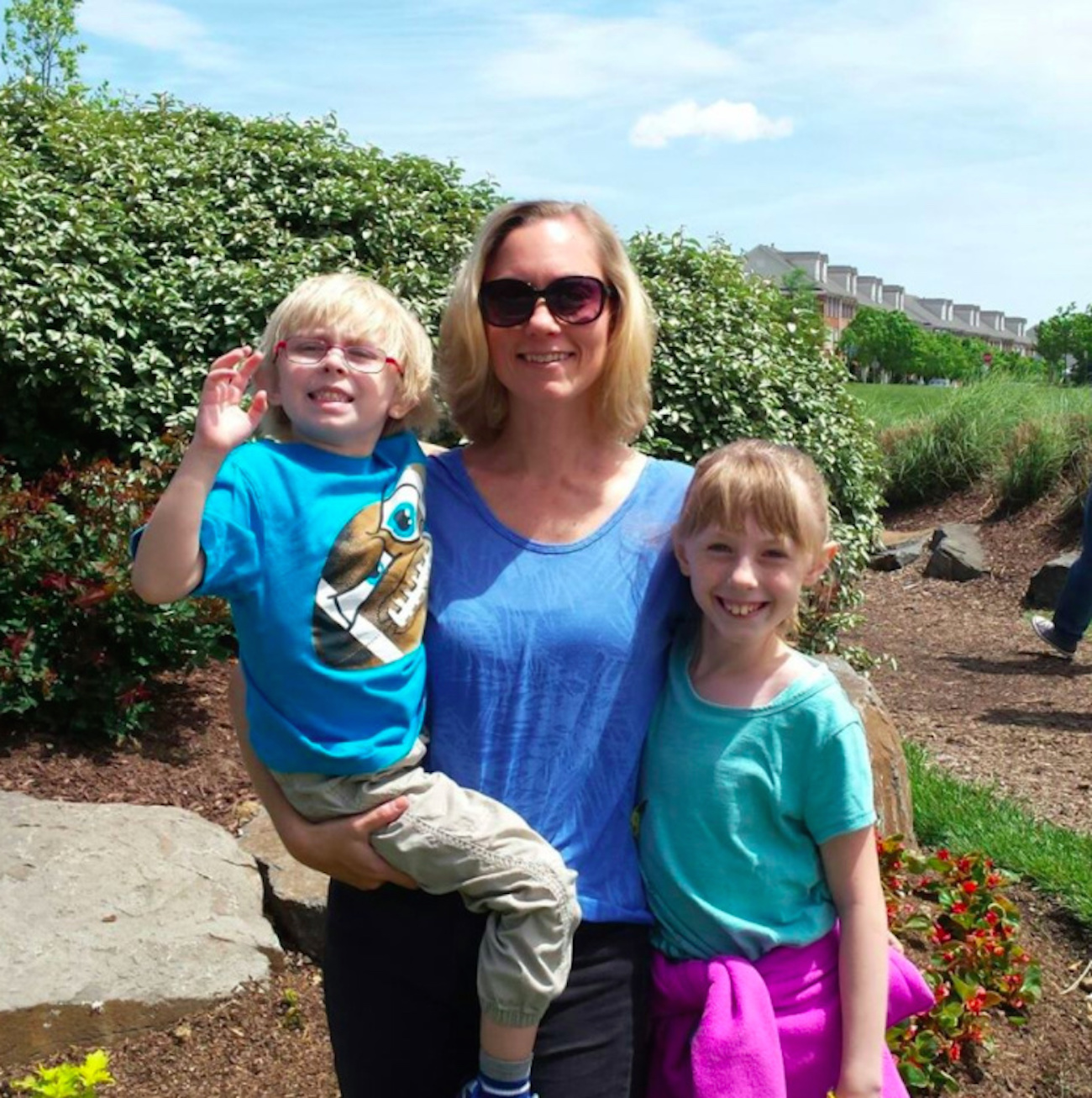 mom holding son and standing next to daughter near garden outdoors