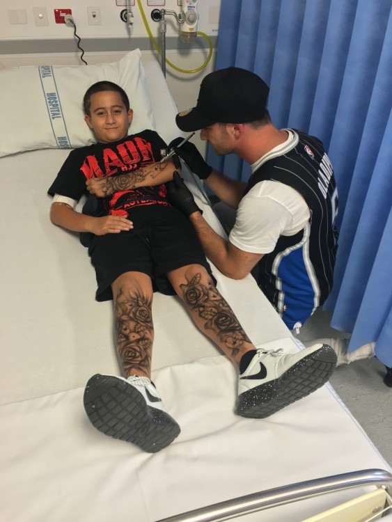 Lloyd giving a tattoo to a child in a hospital bed